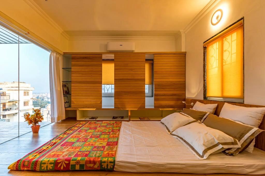 Bedroom bathed in golden hour light with a city view
